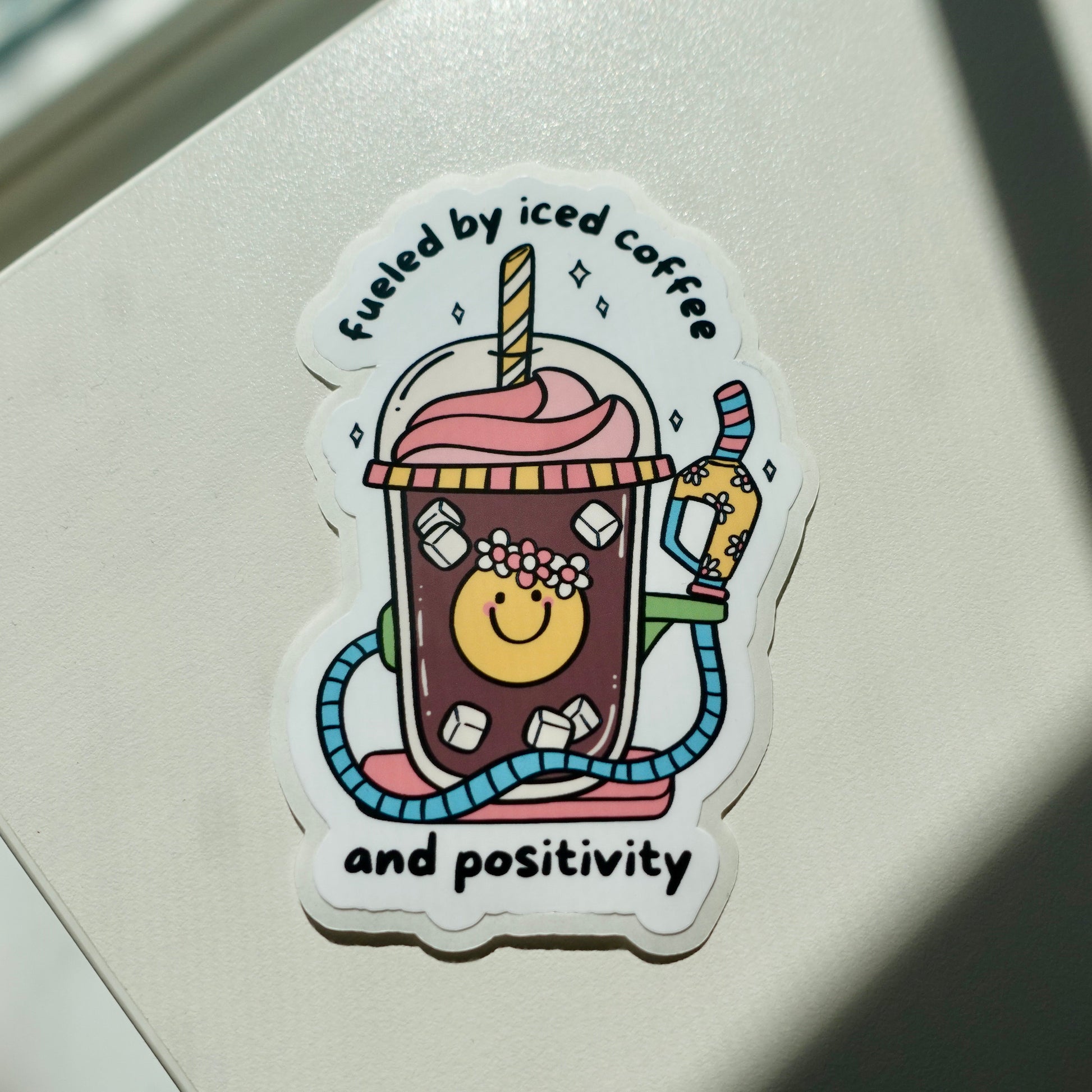 Iced coffee with a colorful gas pump handle with the words Fueled By Iced Coffee And Positivity 