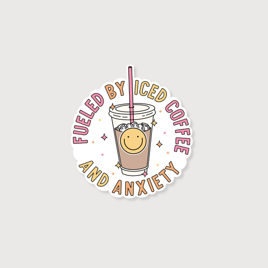 A circular die-cut sticker featuring a cartoon iced coffee cup with a smiling face and the text 'FUELED BY ICED COFFEE AND ANXIETY' in pink and tan lettering, shown on a light gray background.