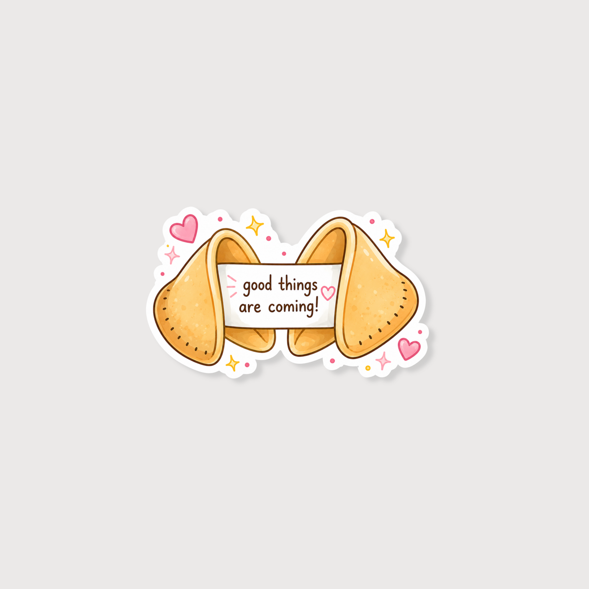 A cute cartoon fortune cookie sticker with the text 'good things are coming!' on a white banner, surrounded by pink hearts, yellow stars, and small pink dots on a light gray background.