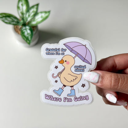 Yellow Duck with a Purple umbrella and Blue boots with the quote Grateful For Where I'm At Excited For Where I'm Going Sticker