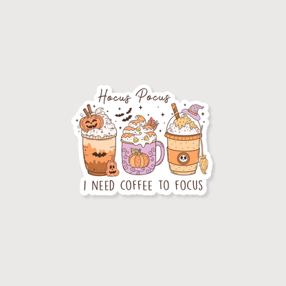 A die-cut sticker featuring three autumn-themed coffee drinks with Halloween decorations and the text 'Hocus Pocus I NEED COFFEE TO FOCUS' on a light gray background.