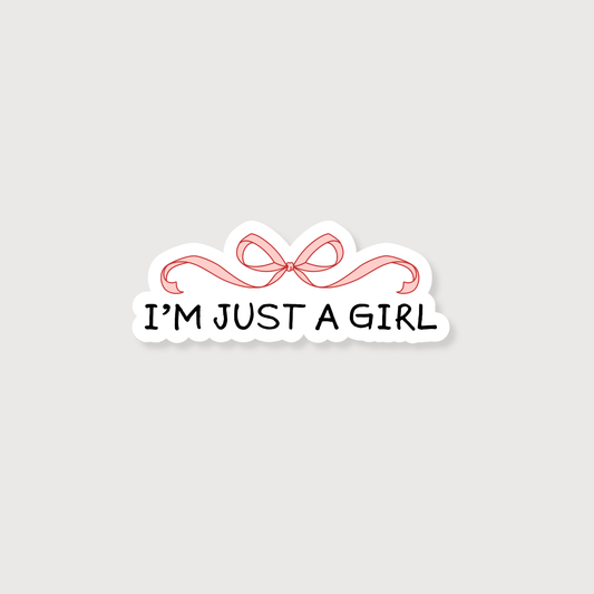 A die-cut sticker with the text 'I'M JUST A GIRL' in black lettering, underlined by a pink ribbon illustration, on a light gray background.