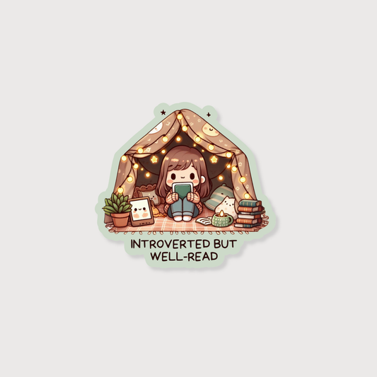 A die-cut sticker featuring a cute cartoon illustration of a girl sitting inside a cozy tent with string lights, surrounded by books, a plant, and a small character card. Below the illustration, the text reads 'INTROVERTED BUT WELL-READ'.