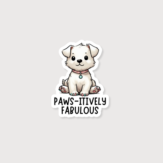 A die-cut sticker featuring a cute cartoon white puppy sitting above the text 'PAWS-ITIVELY FABULOUS' in black lettering, shown on a light gray background.