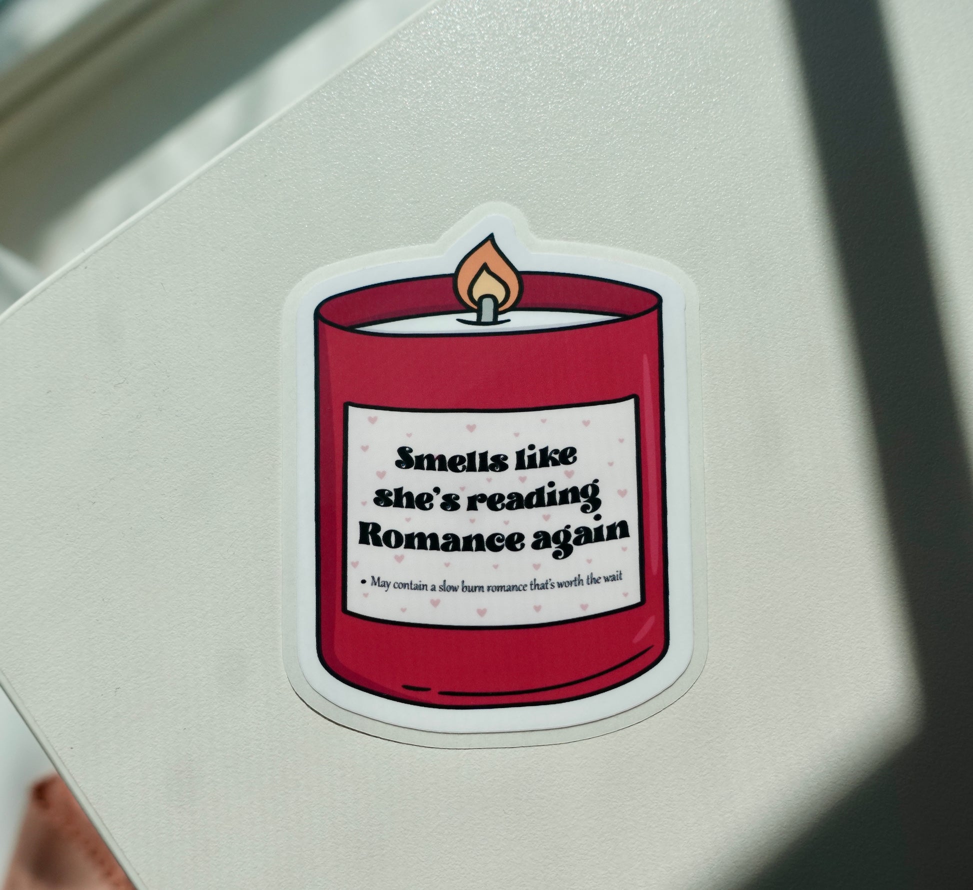 Dark Red candle with the quote Smells Like She's Reading Romance Again Sticker