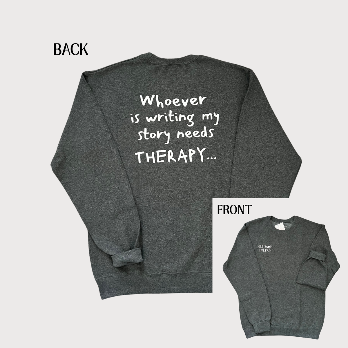 Dark heather gray crewneck sweatshirt shown from both front and back on a light gray background. The back view has large white handwritten-style text reading 'Whoever is writing my story needs THERAPY.